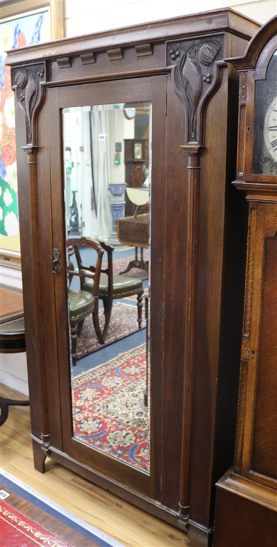 An Edwardian Art Nouveau oak single wardrobe, with mirrored door, flanked by carved tulip panels W.105cm